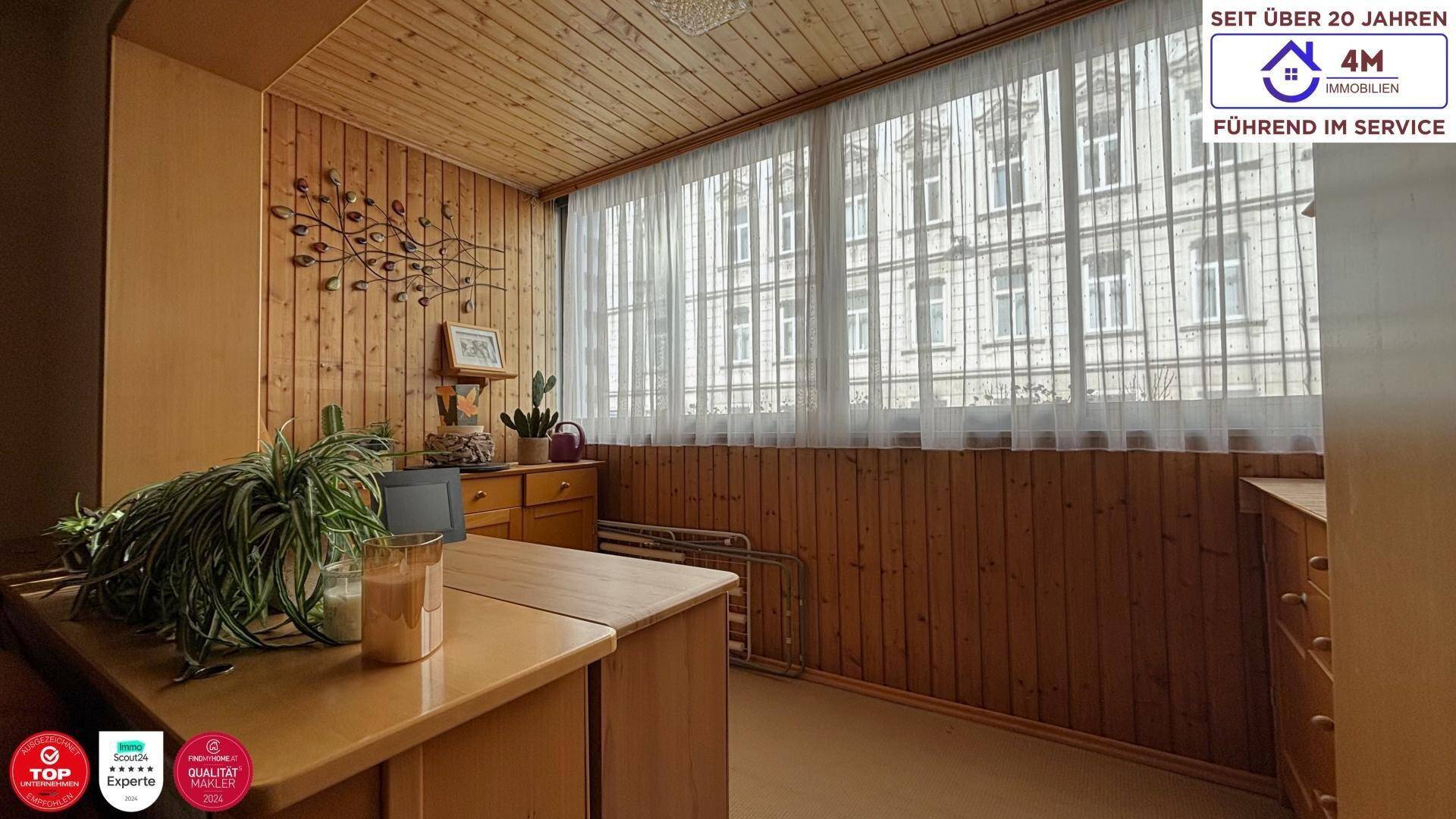 Verglaste Loggia mit Holzverkleidung und weitem Blick auf die umliegenden Gebäude.