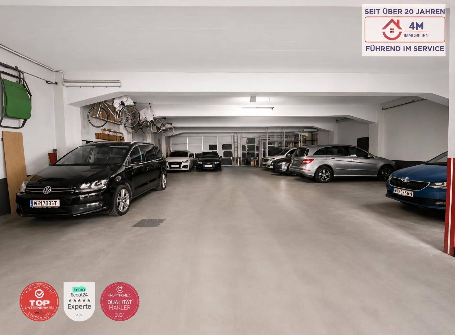 Helle und saubere Tiefgarage mit mehreren geparkten Autos und Fahrrädern an der Decke.