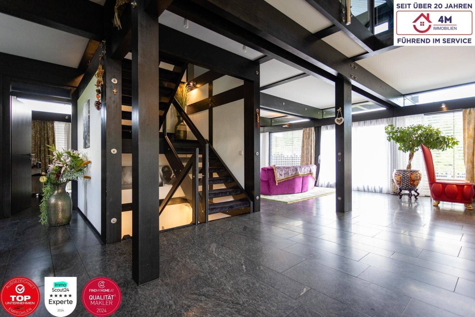 Heller Eingangsbereich mit dunklem Steinboden und offener Treppe zum Obergeschoss.