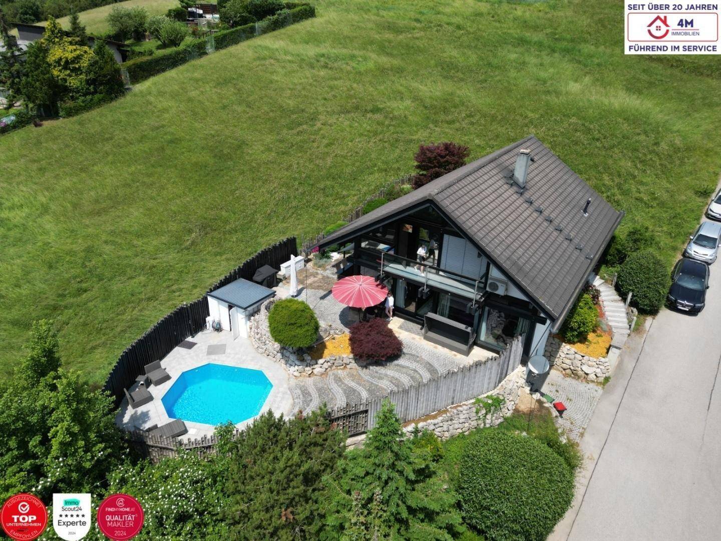 Luftaufnahme des modernen Hauses mit Poolbereich und umliegender grüner Landschaft.