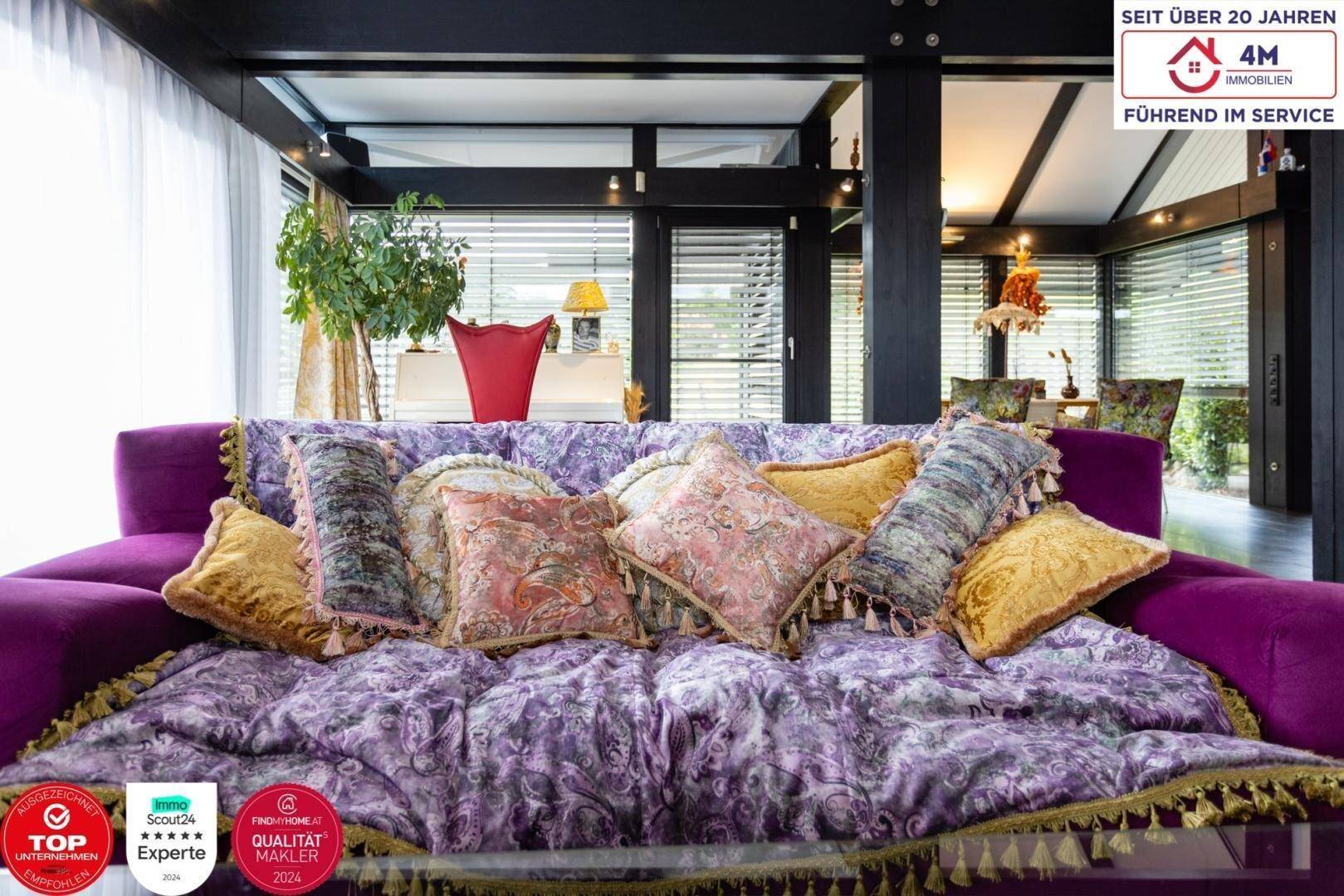 Detailansicht des lila Sofas mit vielen Kissen in einem hellen Wohnzimmer.