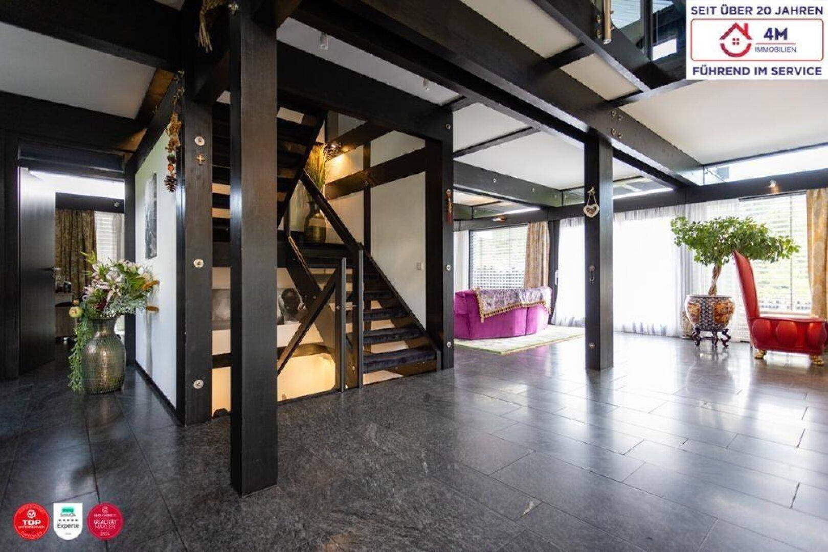 Heller Eingangsbereich mit dunklem Steinboden und offener Treppe zum Obergeschoss.