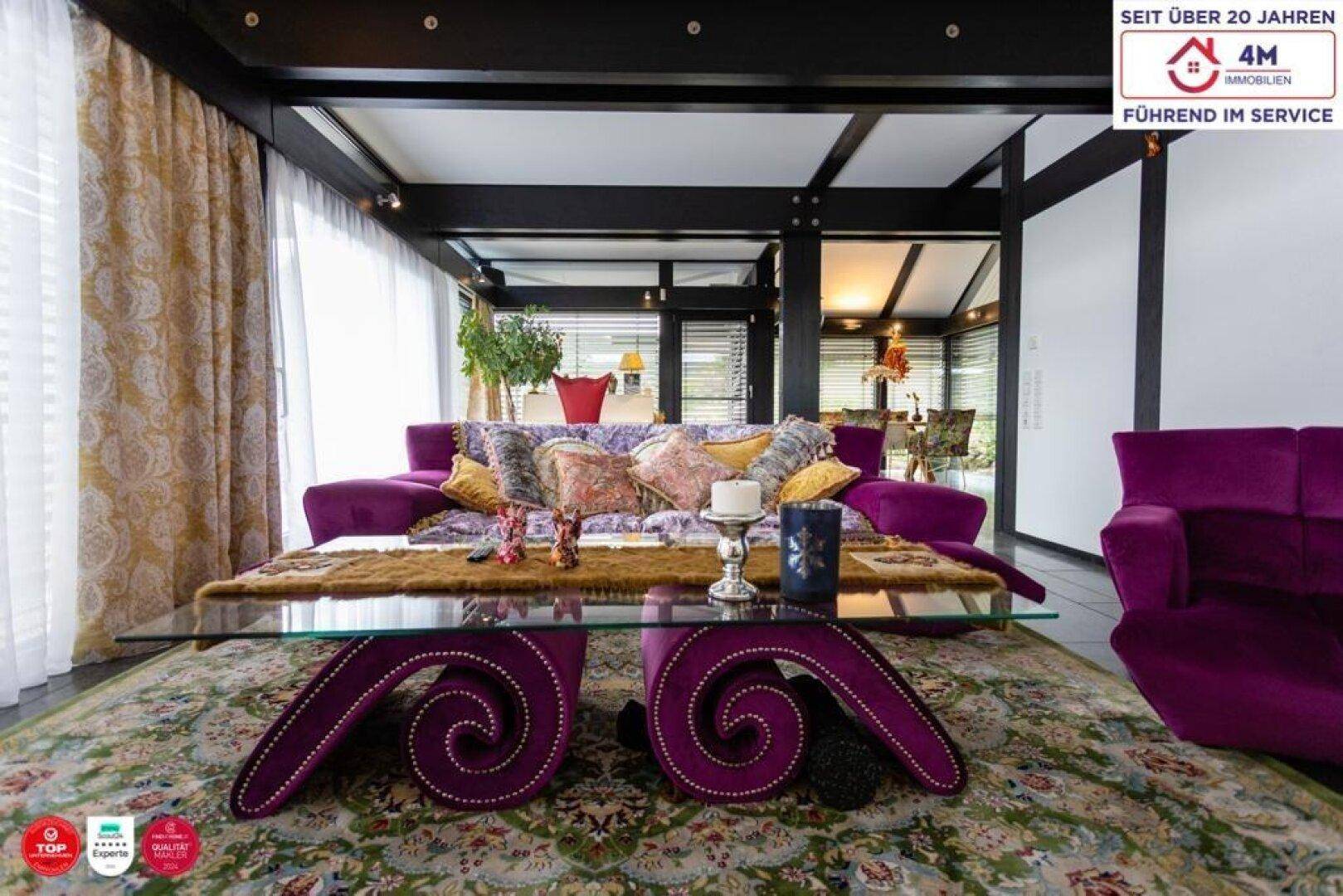 Geräumiges Wohnzimmer mit lila Sofa, Teppich und Blick auf den Essbereich.