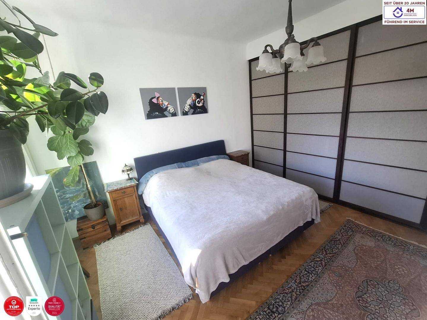 Gemütliches Schlafzimmer mit Doppelbett, Parkettboden und großem Schiebetürenschrank.