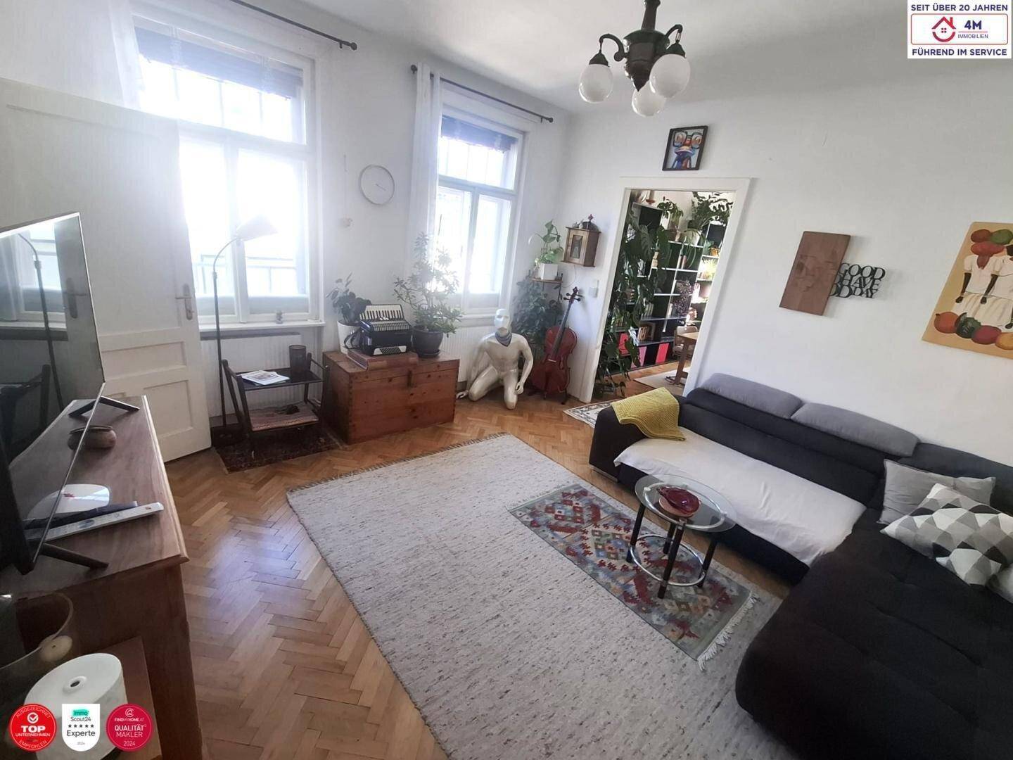 Helles Wohnzimmer mit Parkettboden, bequemer Couch und großen Fenstern für viel Tageslicht.