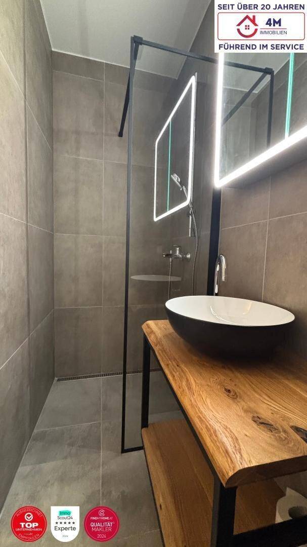 Modernes Badezimmer mit begehbarer Dusche, stilvollem Waschbecken und großen Fliesen.
