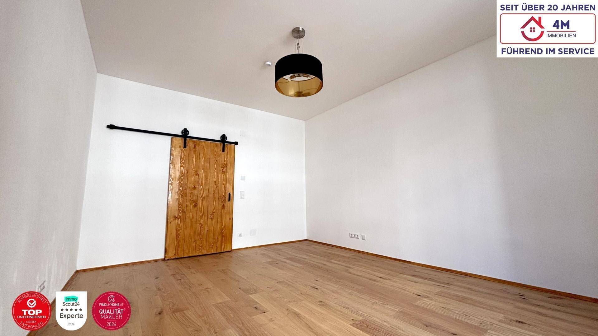 Geräumiges Zimmer mit Holzboden und moderner Schiebetür aus Holz, ideal für flexible Nutzung.