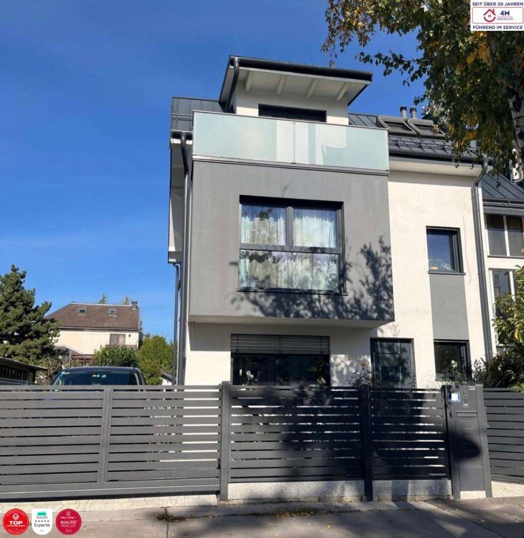 Moderne Hausfassade mit grauen Akzenten und einem Balkon im Obergeschoss.