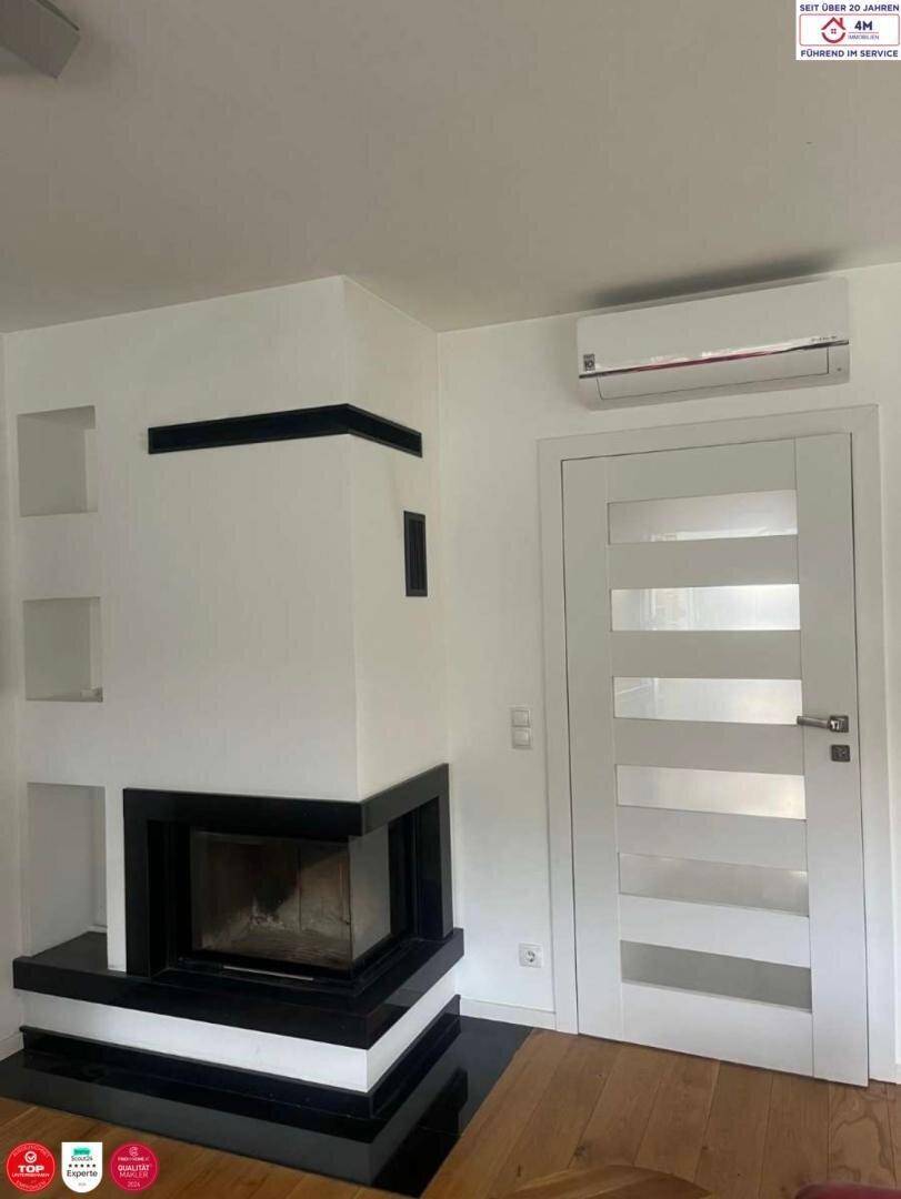 Moderner Kamin mit schwarzem Akzent in einem hellen Wohnraum mit Holzboden.