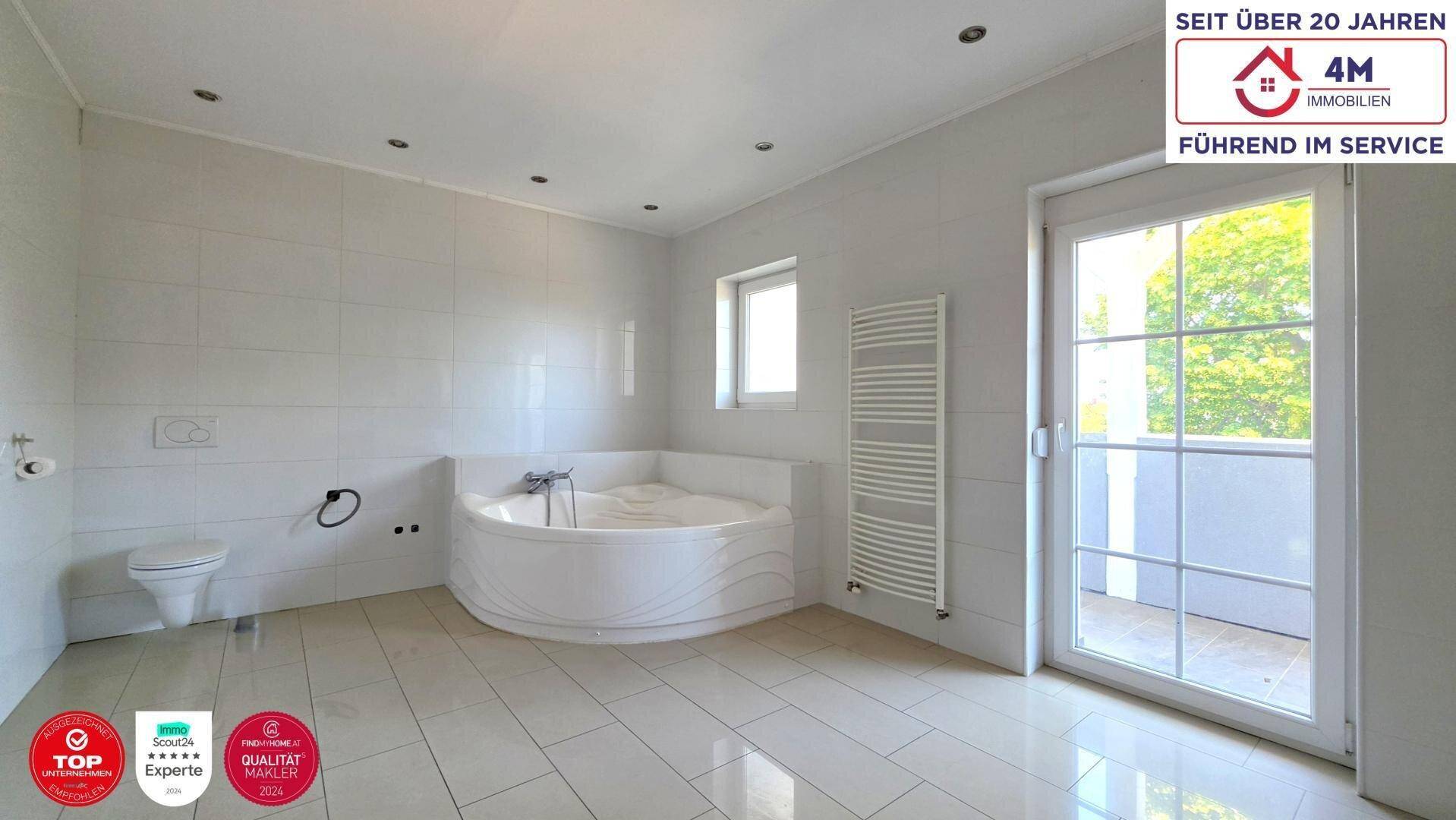 Modernes Badezimmer mit Eckbadewanne, Wand-WC, beheiztem Handtuchhalter und Zugang nach draußen.