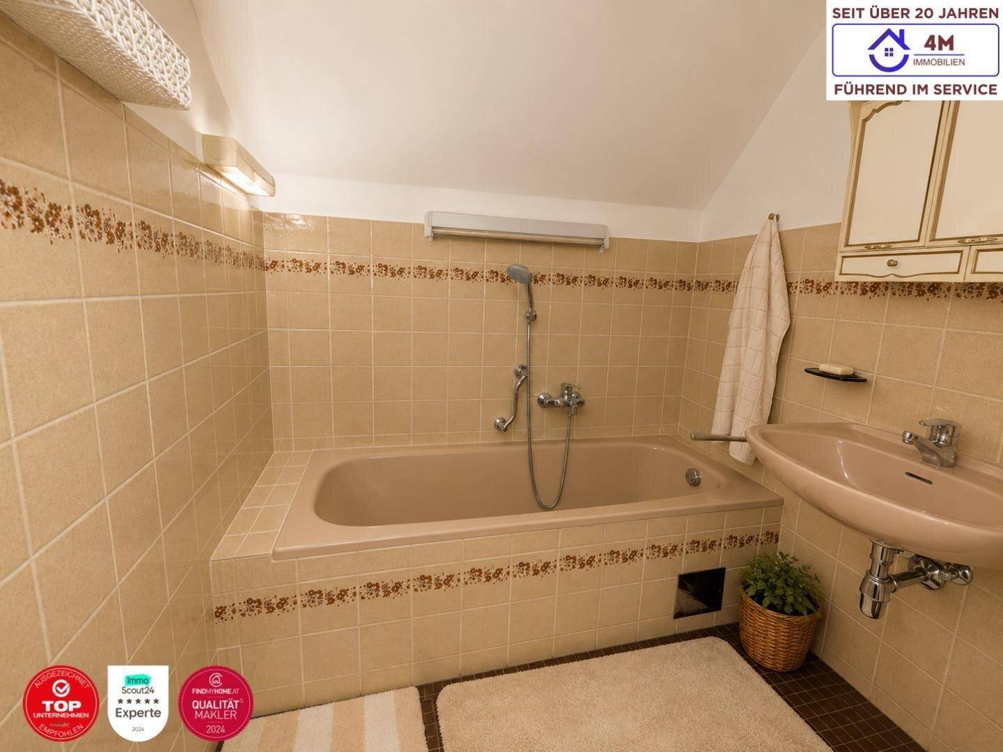 Klassisches Badezimmer mit Badewanne, Einzelwaschbecken und beigefarbenen Fliesen im traditionellen Stil.