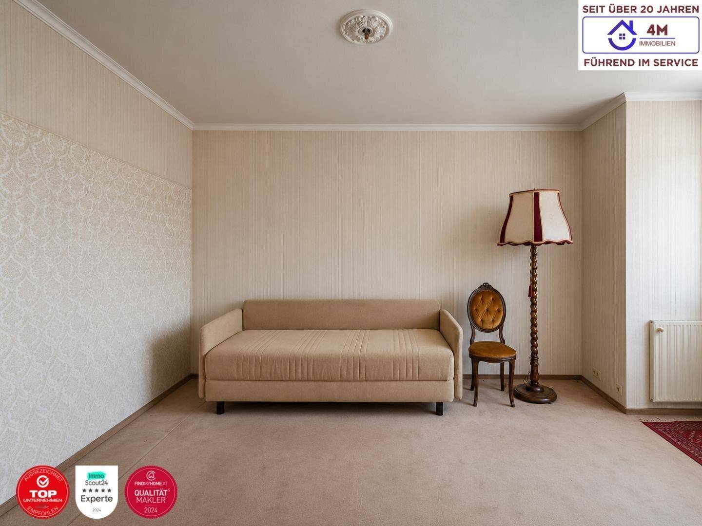 Helles Wohnzimmer mit beigem Sofa, Stehlampe und Teppichboden, das eine klassische Atmosphäre bietet.