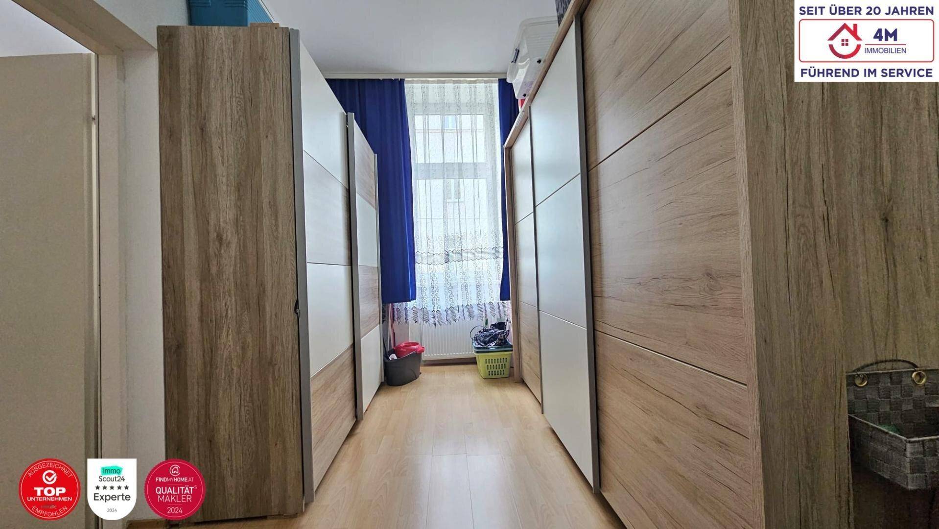 Schlafzimmer mit blauen Vorhängen, Holzboden und geräumigen Schiebetürenschränken.
