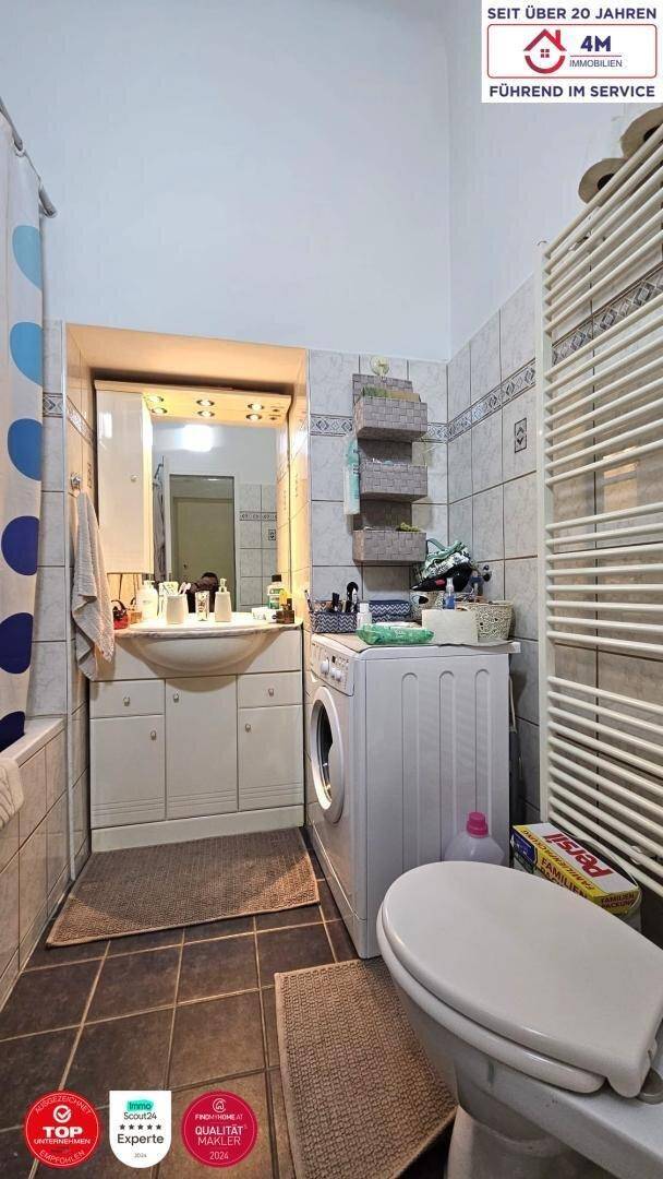 Badezimmer mit Waschbecken, Toilette, Duschvorhang und beheiztem Handtuchhalter.