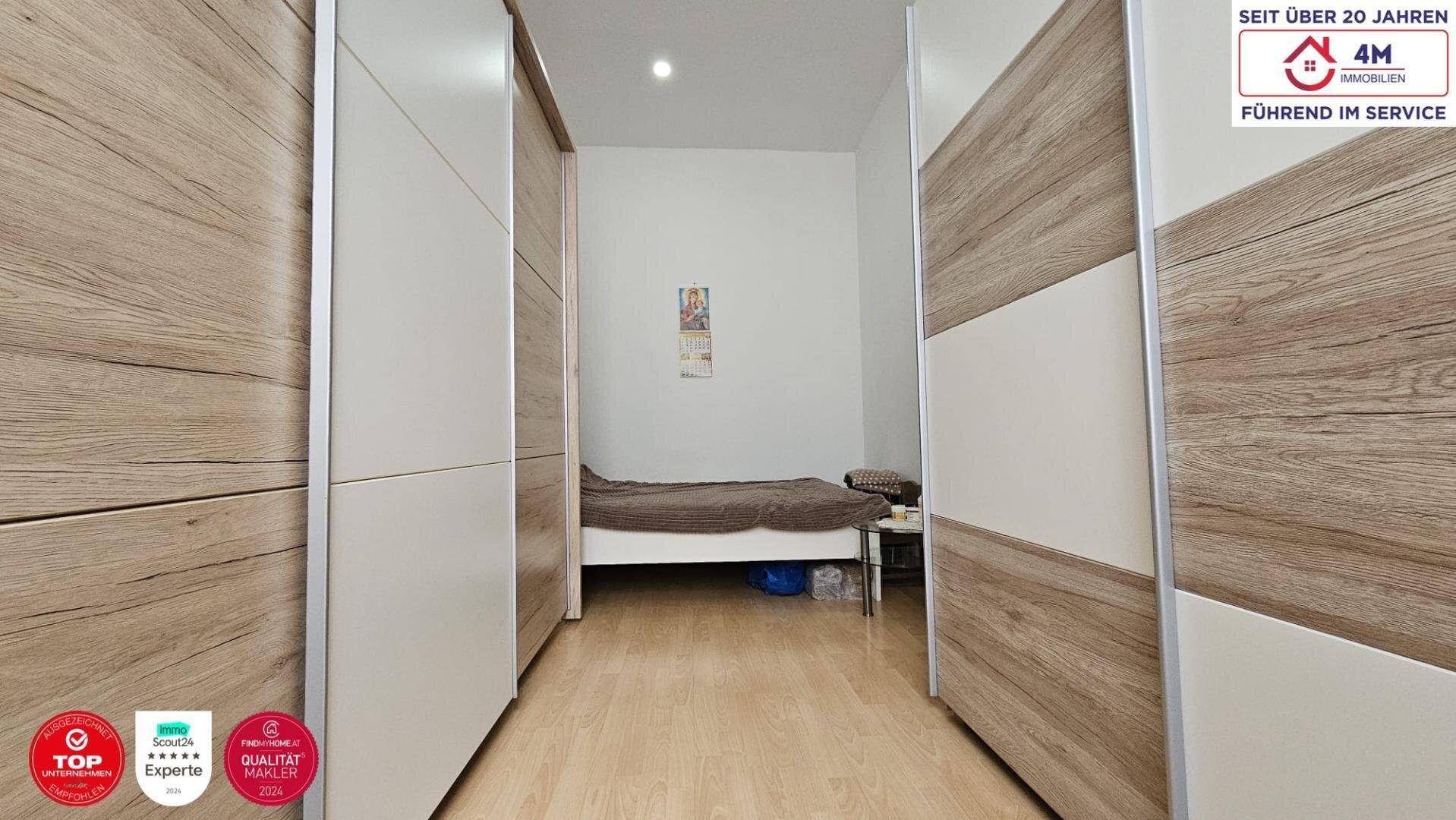 Schlafzimmer mit Holzboden und großen Schiebetürenschränken, die viel Stauraum bieten.