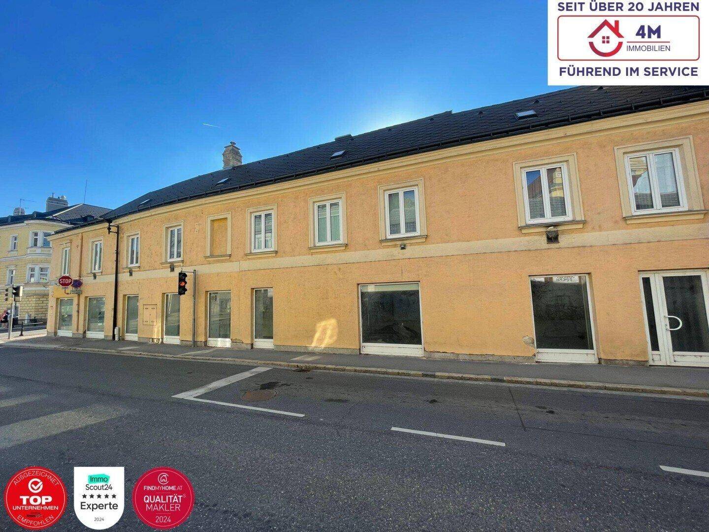 Lange Fassade eines Gebäudes an einer Straße mit vielen Fenstern und klarem Himmel.