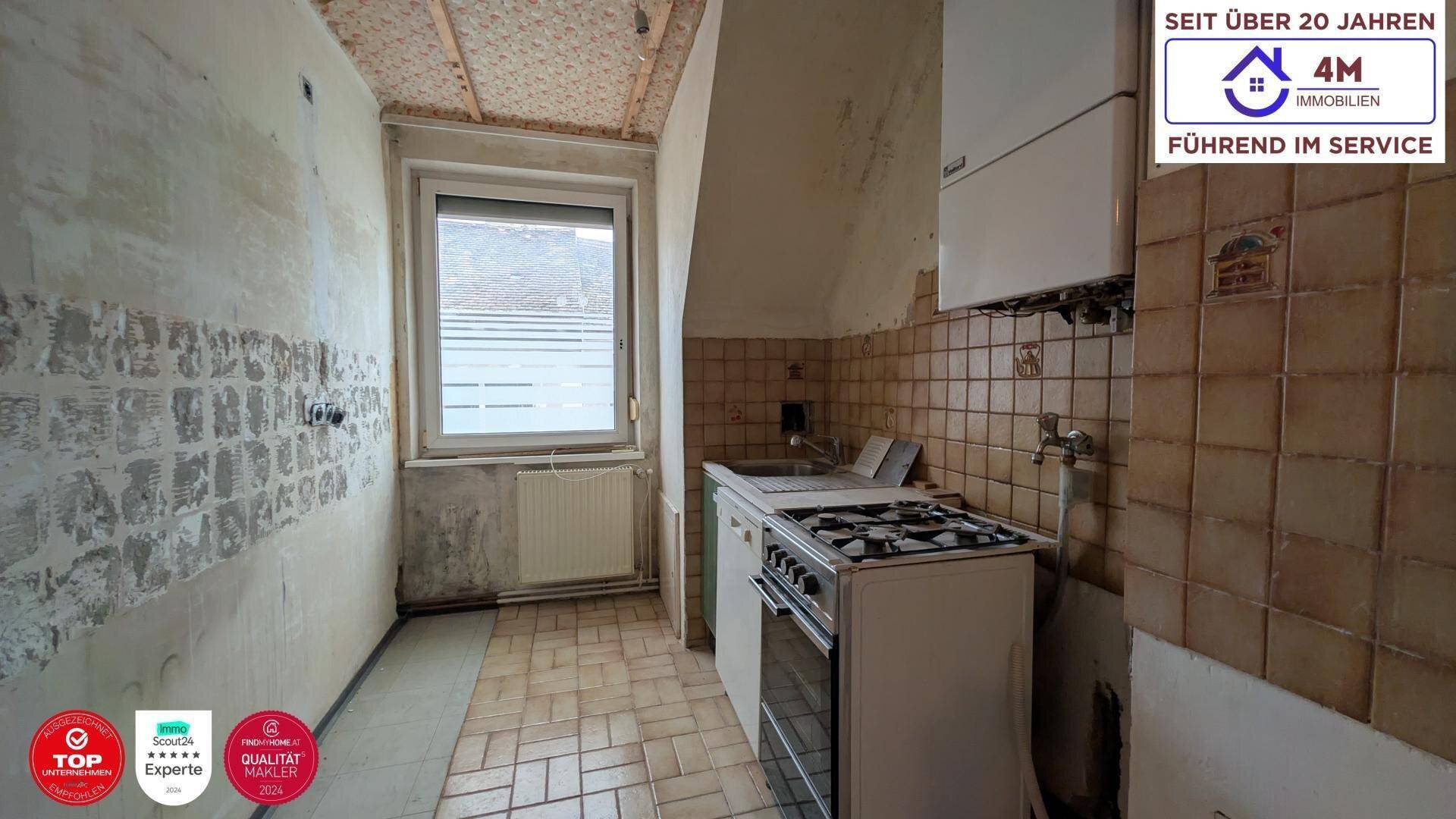Alte Küche mit Gasherd, Spüle und Fliesen, benötigt eine vollständige Renovierung.