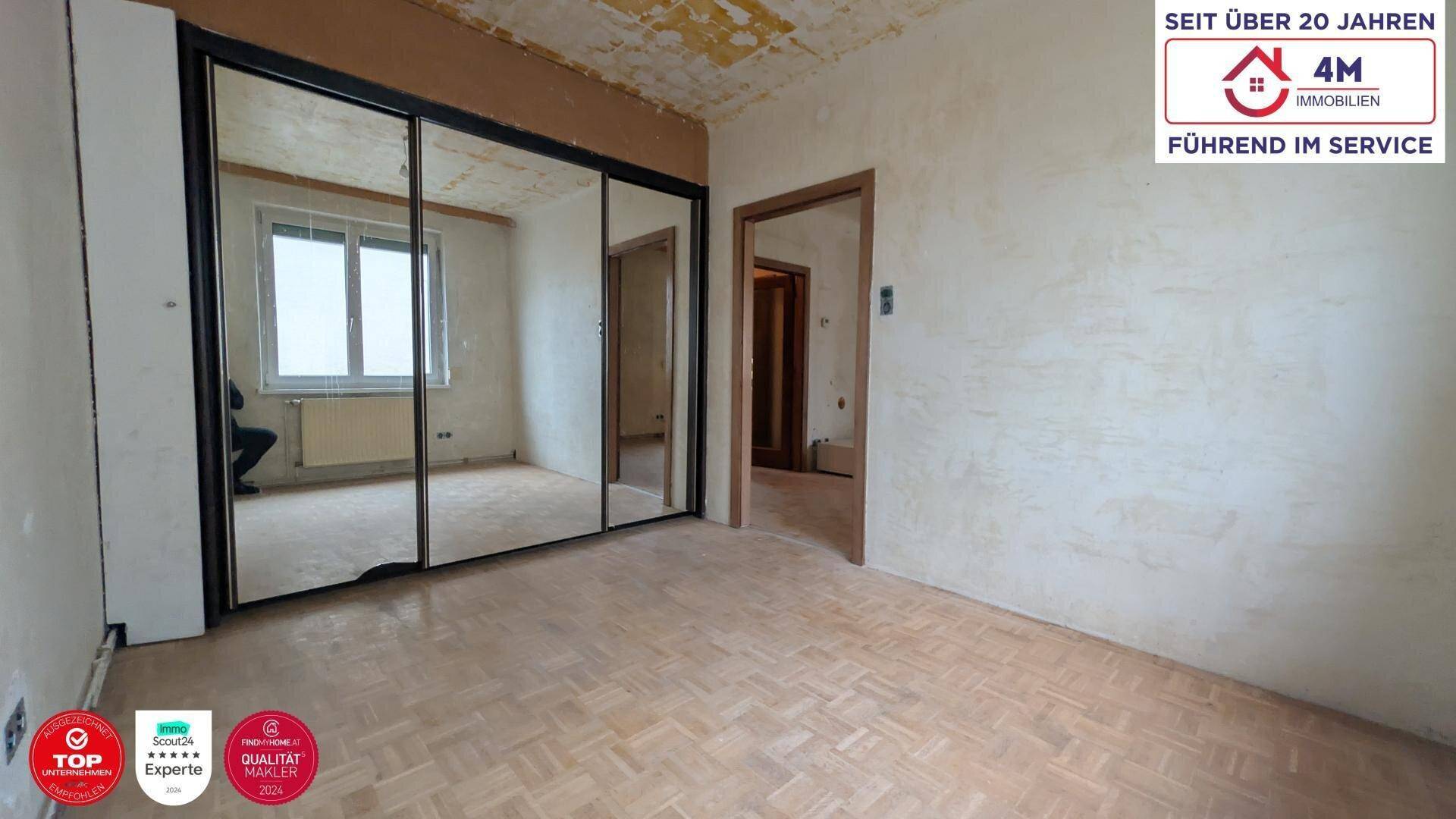 Unrenoviertes Schlafzimmer mit Spiegelschrank, Parkettboden und Renovierungsbedarf.