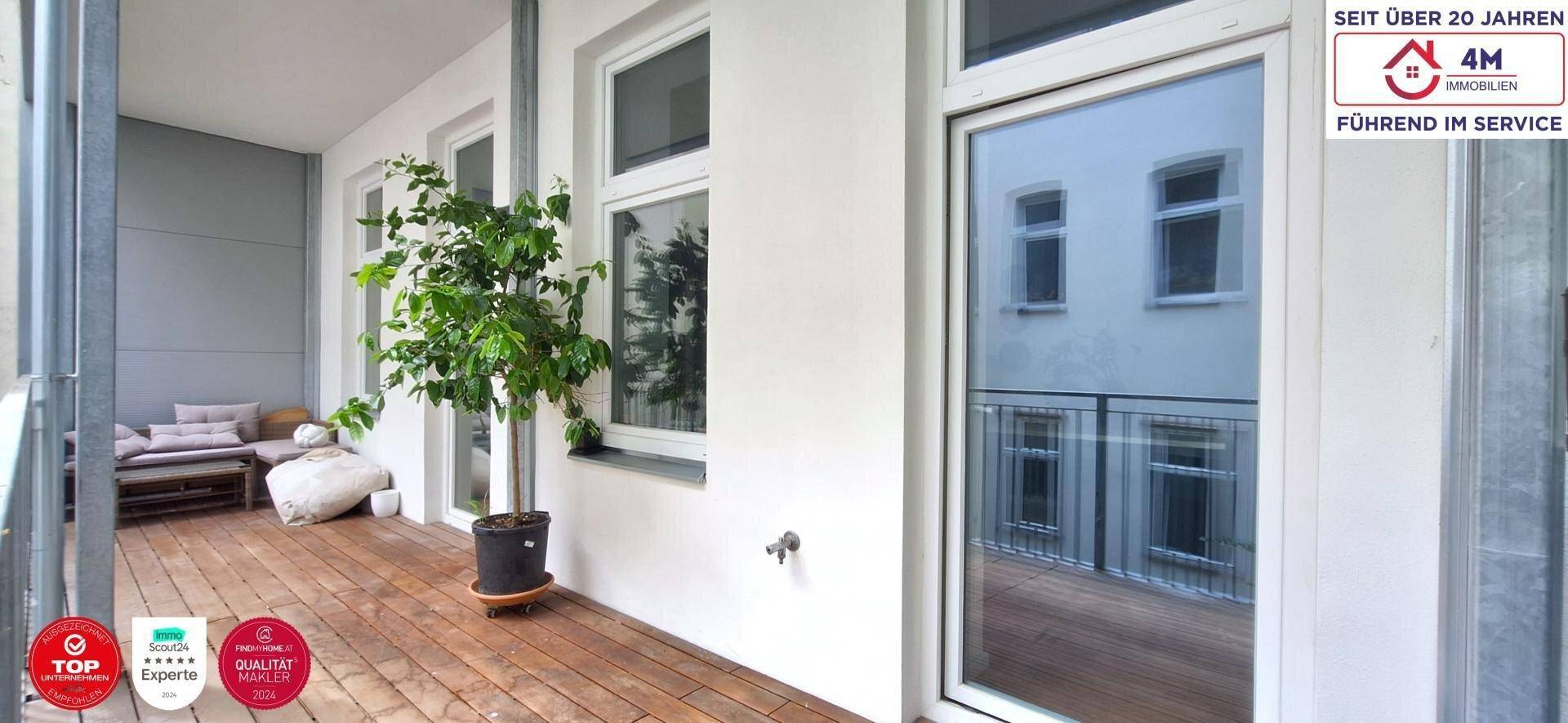 Heller Balkon mit Holzboden, Pflanzen und Sitzgelegenheiten, ideal zum Entspannen im Freien.