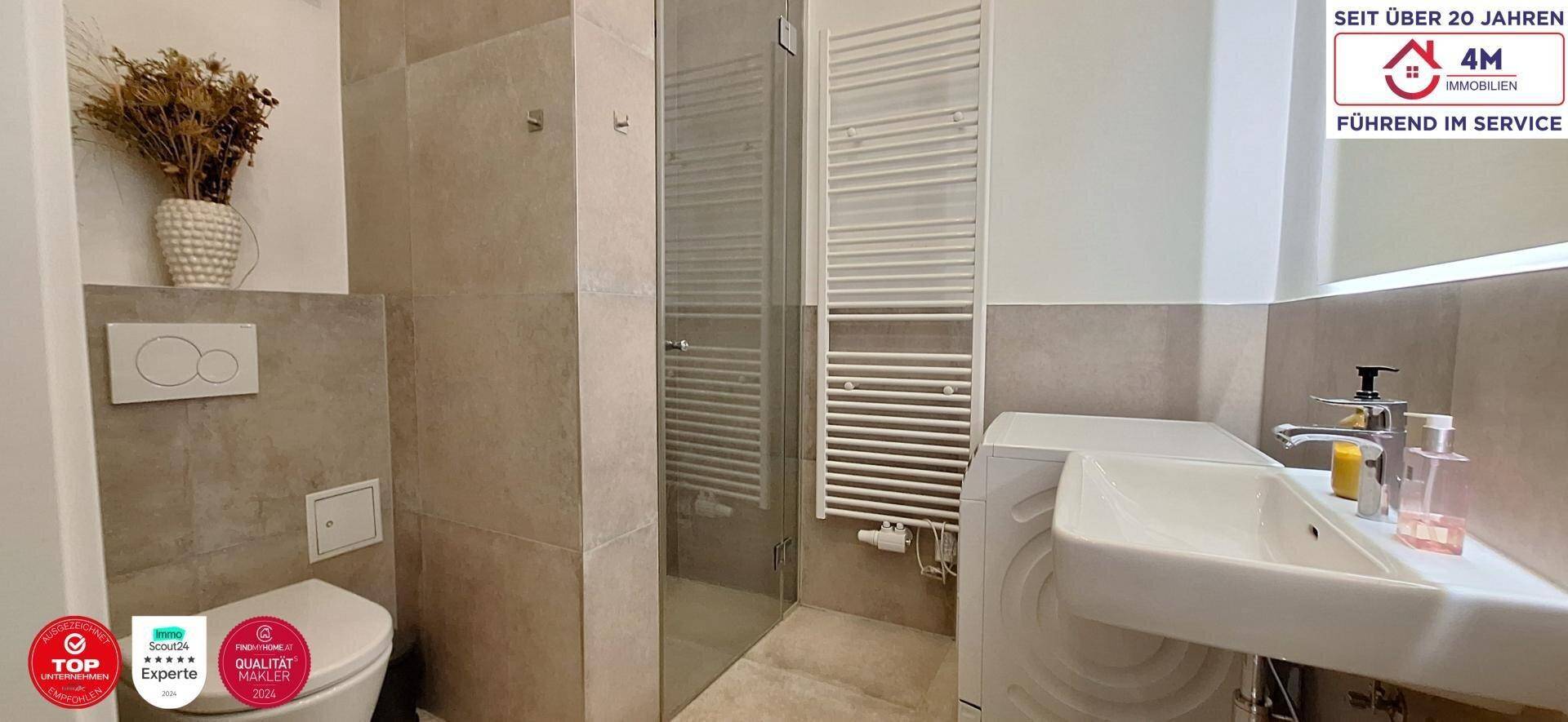 Modernes Badezimmer mit Dusche, WC, Waschbecken und beheiztem Handtuchhalter in neutralen Tönen.