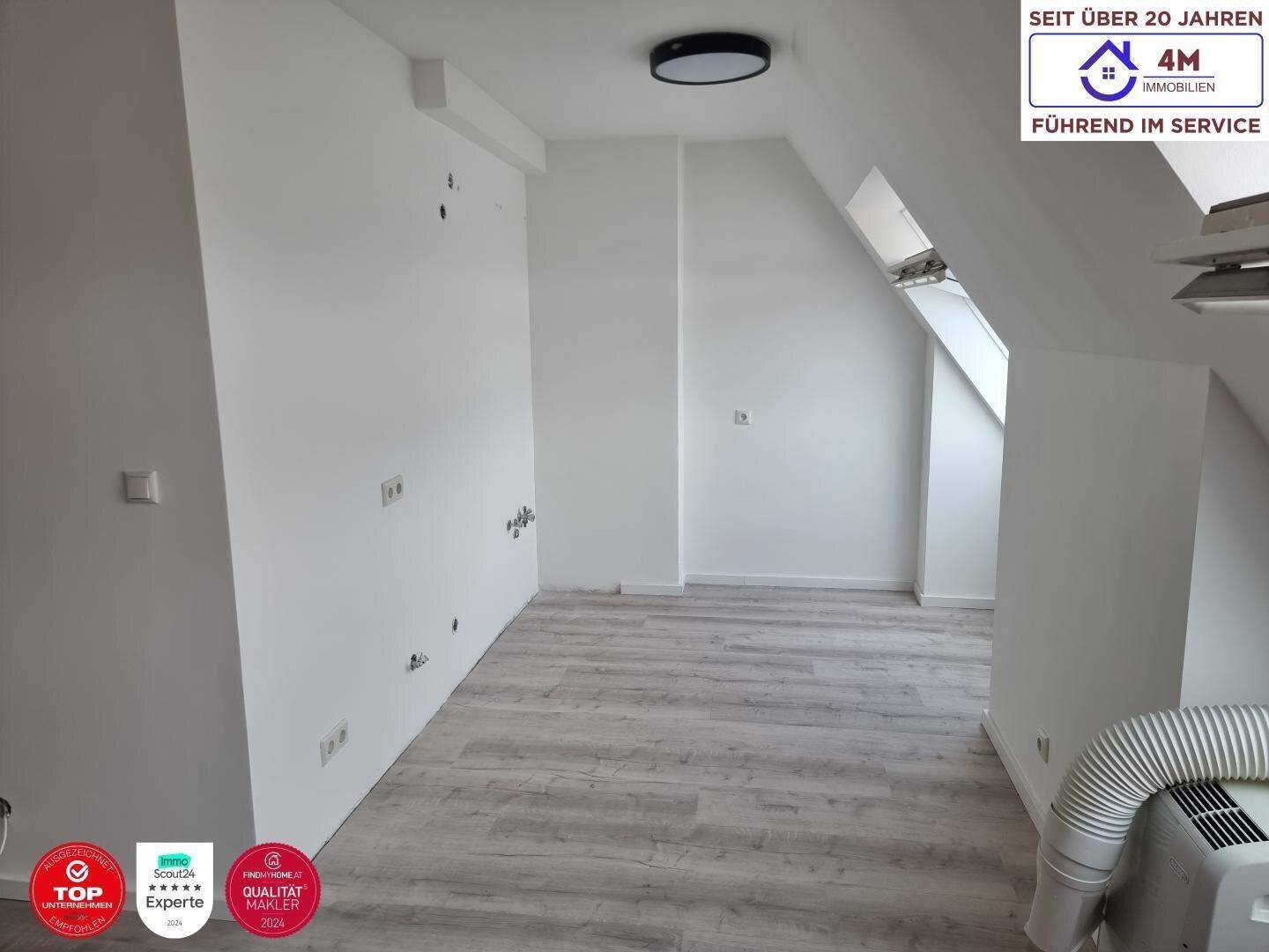 Leeres Zimmer im Dachgeschoss mit hellen Wänden und Laminatboden, bereit zur individuellen Gestaltung.