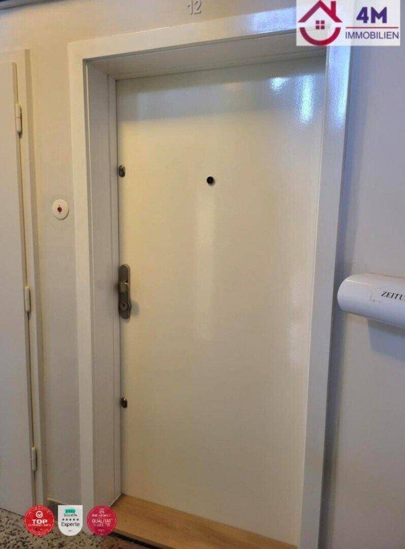 Eingangstür einer Wohnung mit weißer Oberfläche und einem Türspion, typisch für einen Flur.
