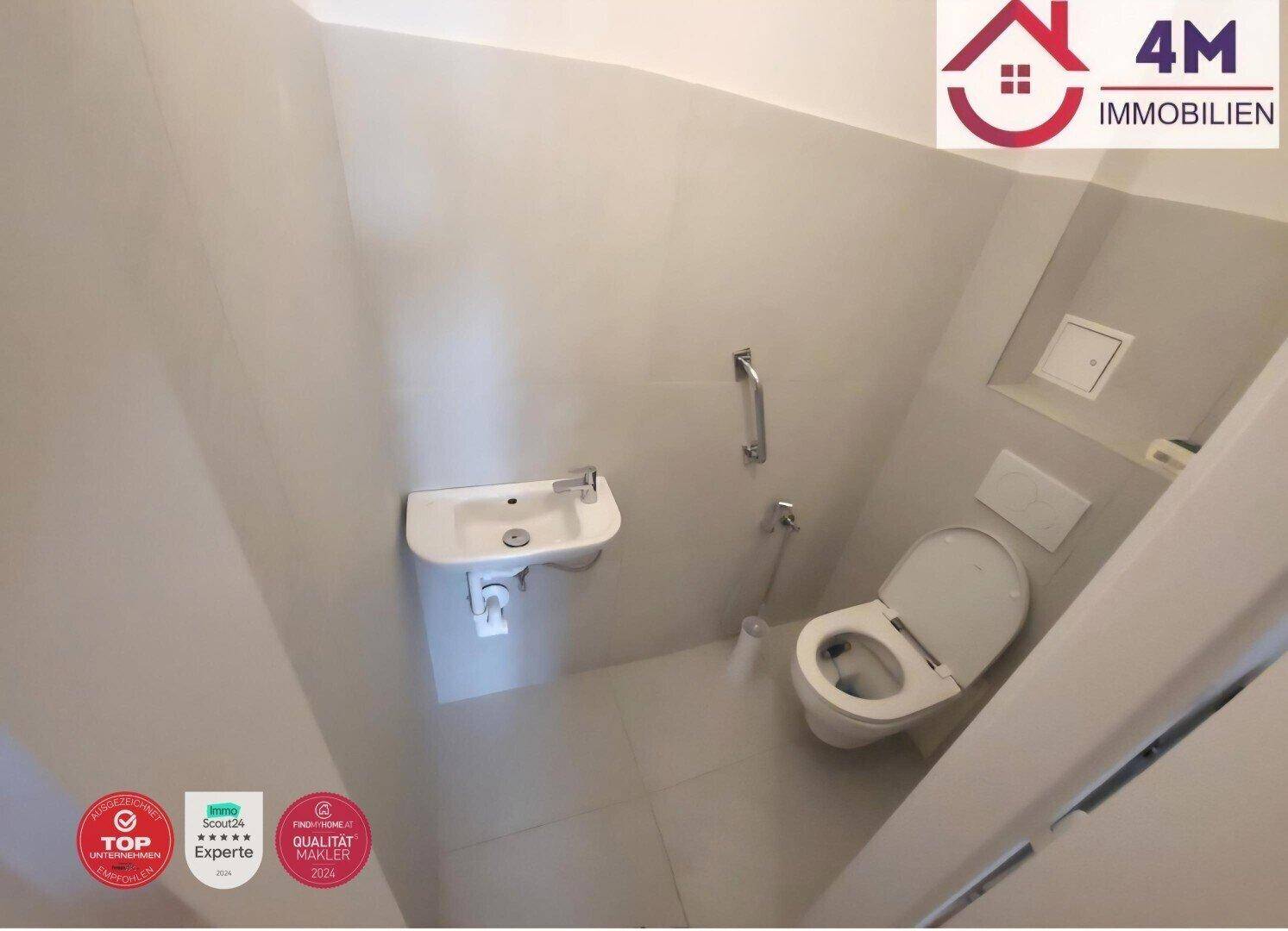 Kleines Gäste-WC mit Wand-WC, Handwaschbecken und Haltegriff für zusätzliche Sicherheit.