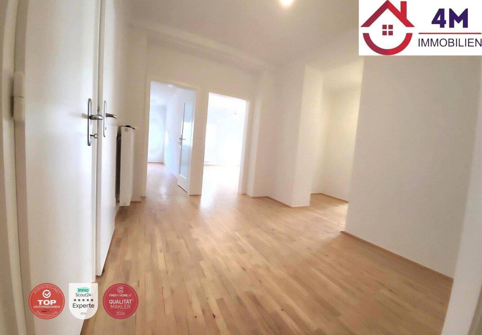 Langer Flur mit hellem Parkettboden und Zugang zu mehreren Zimmern der Wohnung.