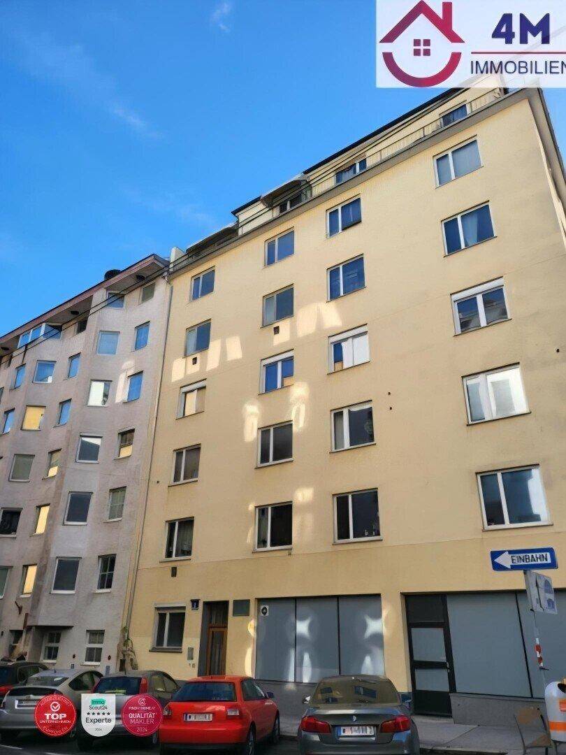 Mehrstöckiges Wohngebäude mit gelber Fassade und vielen Fenstern an einer Stadtstraße.