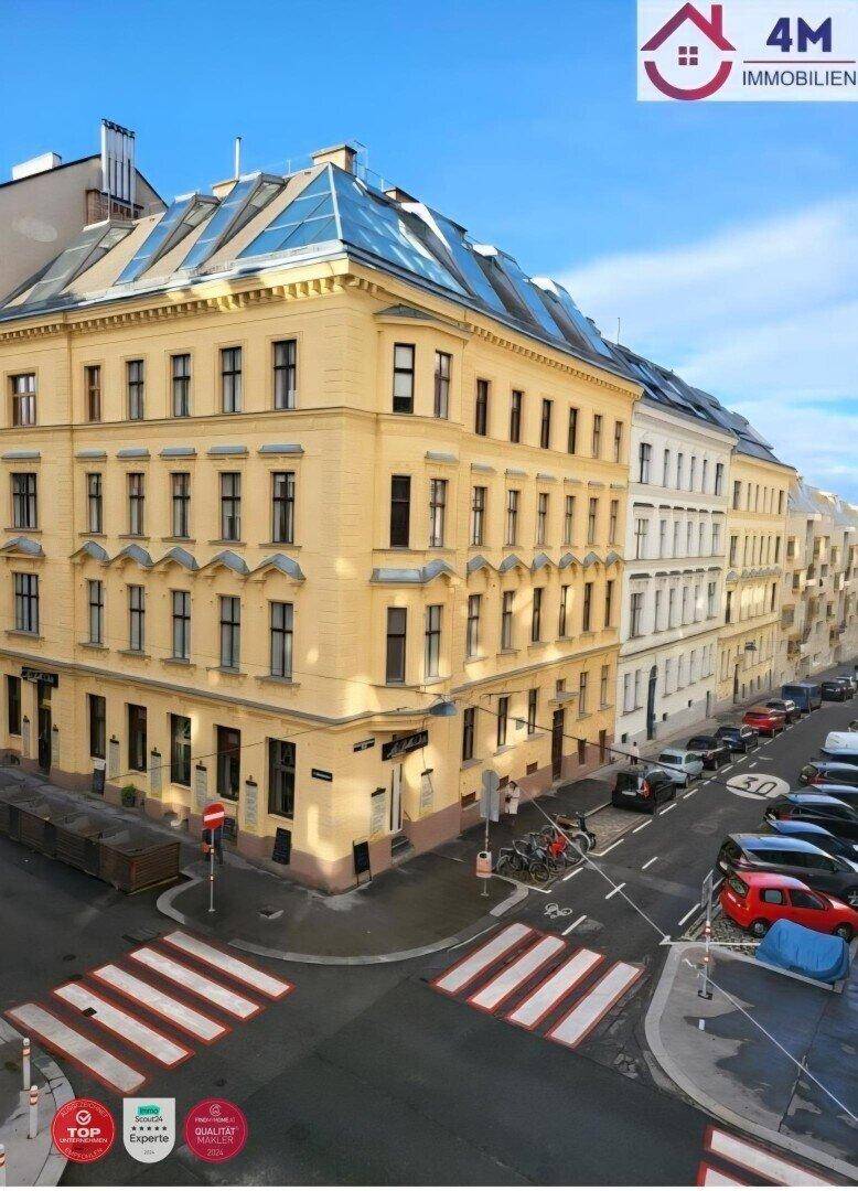 Historisches Eckgebäude in einer belebten Stadtstraße mit vielen Fenstern und Geschäften.