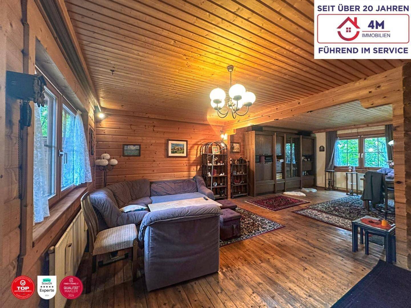 Gemütliches Wohnzimmer im Landhausstil mit Holzwänden, Holzdecke und bequemen Sofas.