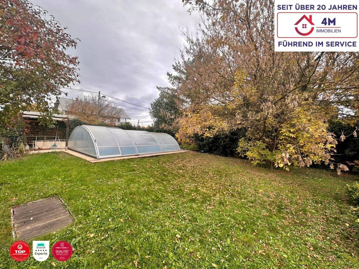 Großer Gartenbereich mit Rasenfläche und einem überdachten Swimmingpool.
