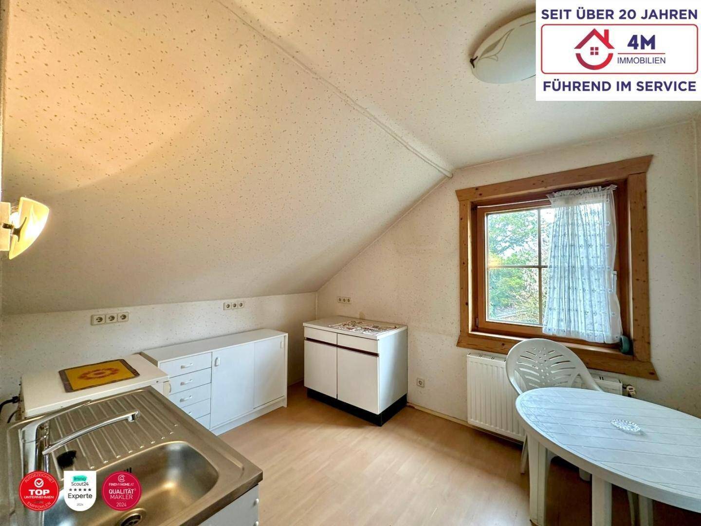 Kleine Küchenzeile im Dachgeschoss mit Spüle und Stauraum, ideal für ein Studio.