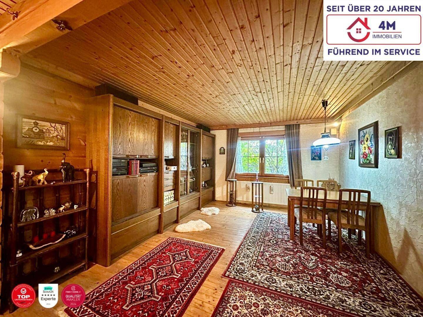 Rustikaler Wohn-Essbereich mit Holzboden, Holzdecke und traditionellen Teppichen.