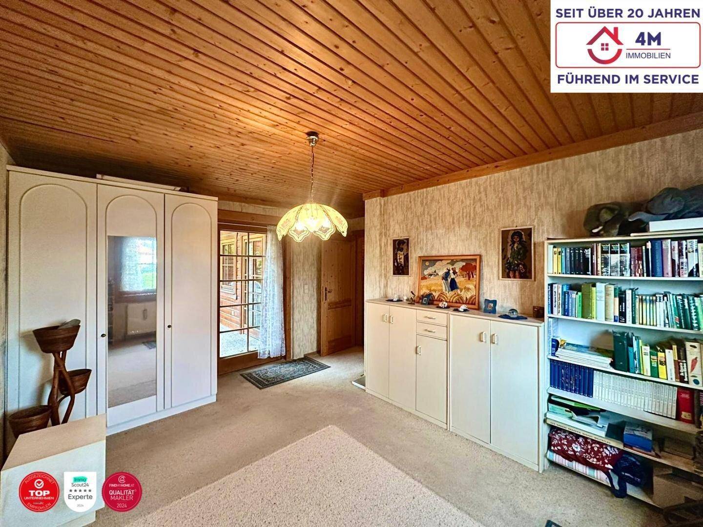 Schlafzimmer mit Teppichboden, Einbauschränken und Zugang zu einem Balkon.
