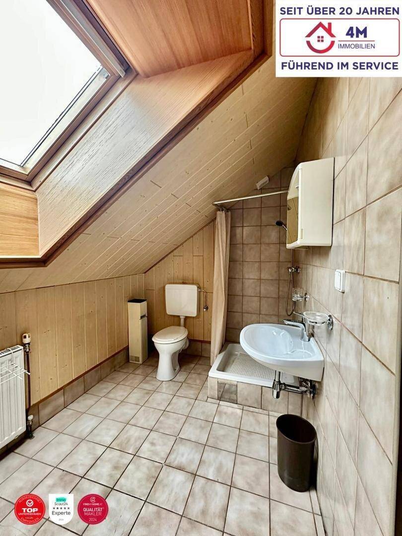 Badezimmer im Dachgeschoss mit Dusche, WC und Dachfenster für natürliches Licht.