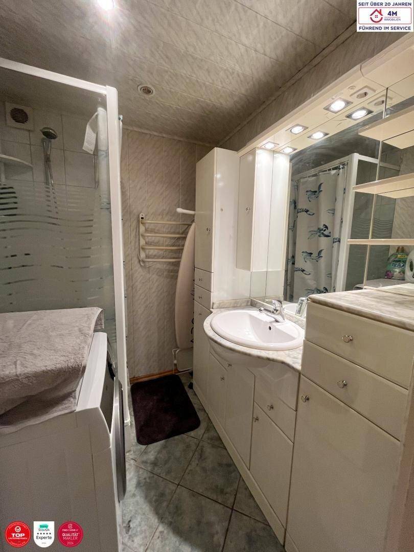 Badezimmer mit Dusche, Waschbecken und Spiegelschrank.