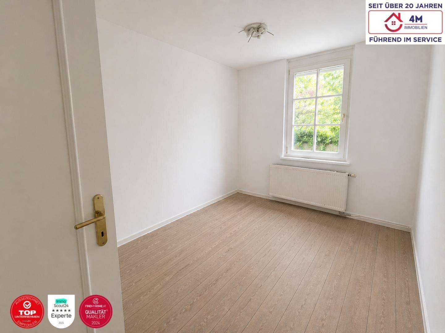 Helles Zimmer mit Laminatboden und Fenster zum Garten, ideal als Schlaf- oder Arbeitszimmer.
