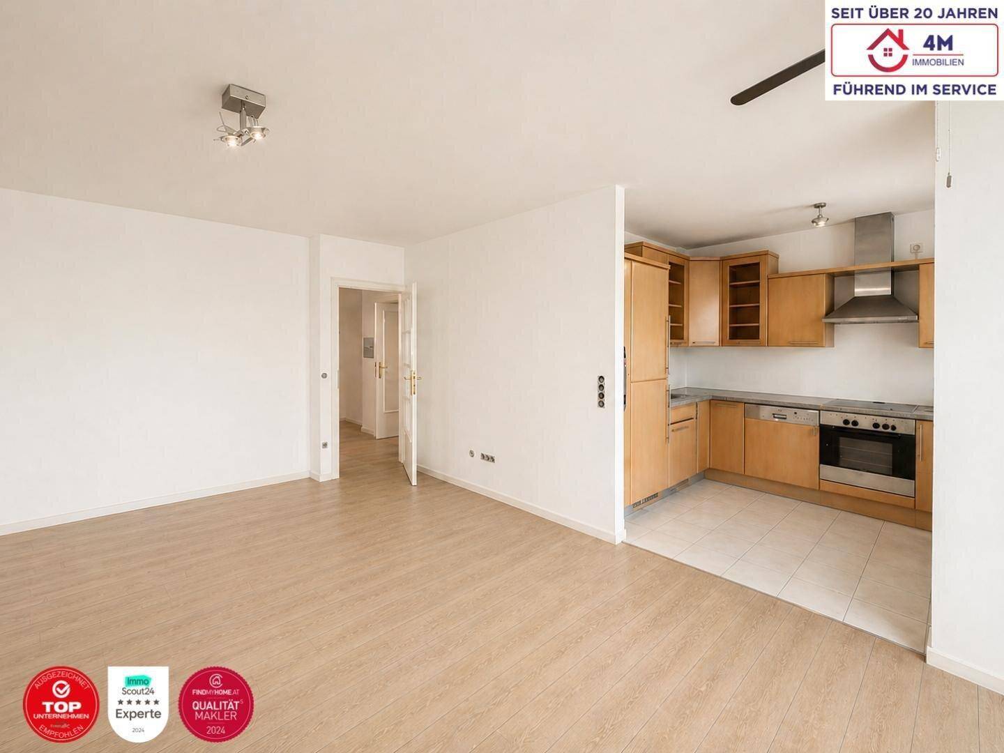 Offener Wohnbereich mit Laminatboden und angrenzender Küche, ideal für modernes Wohnen.