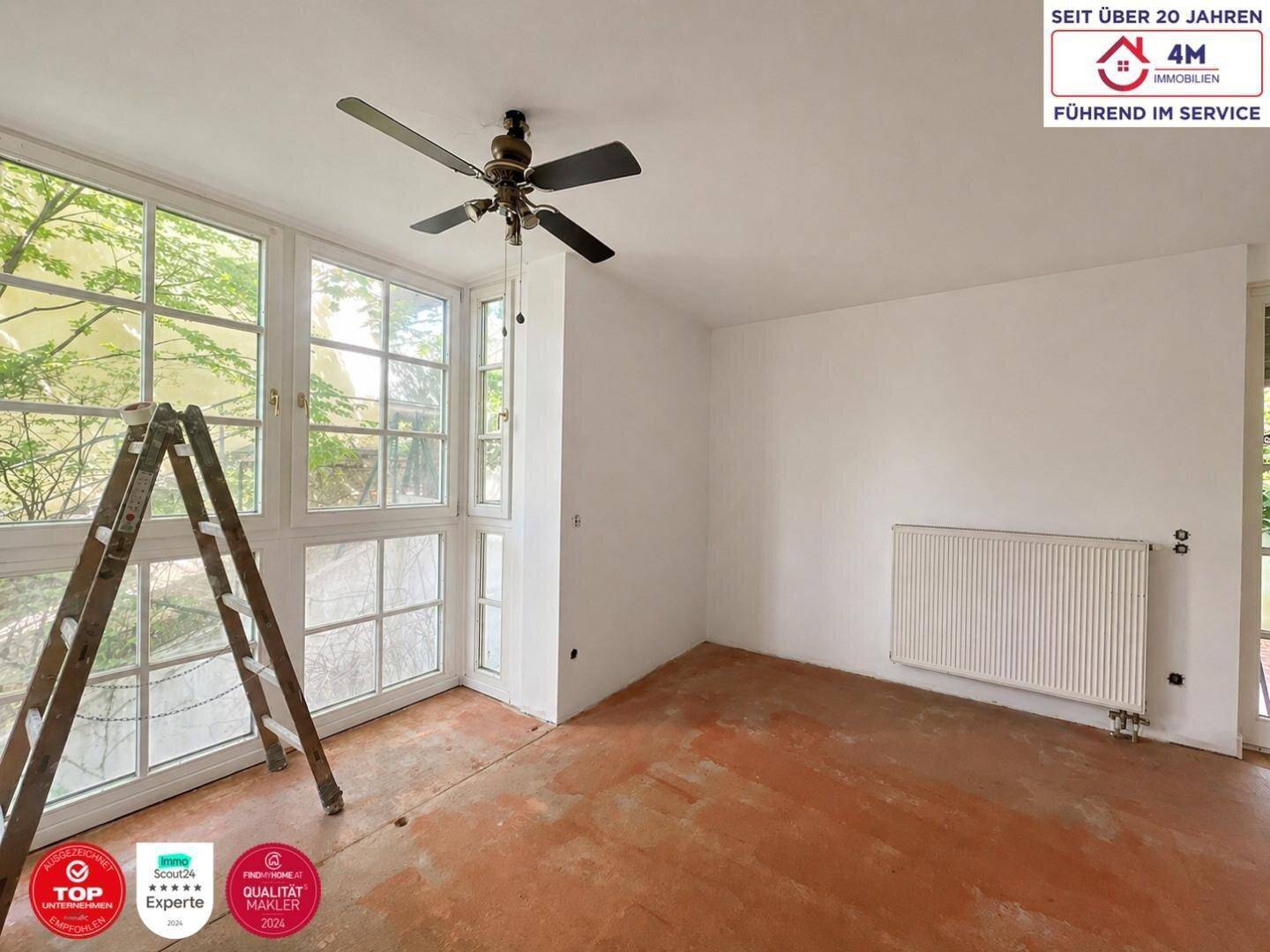 Geräumiges Zimmer mit großen Fenstern, Deckenventilator und unfertigem Bodenbelag.