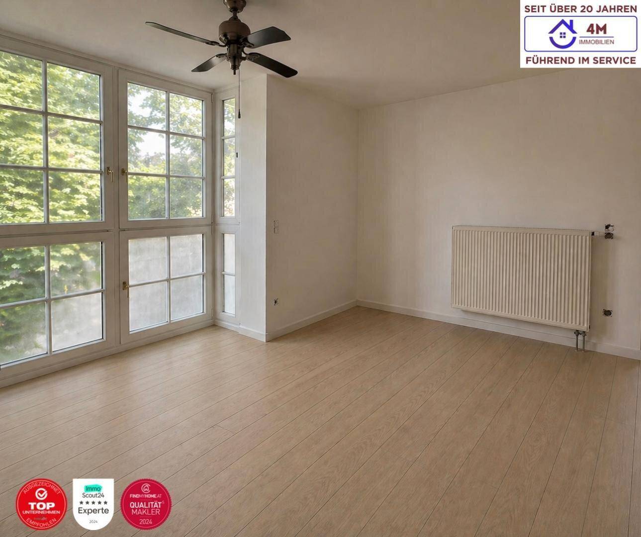 Helles Zimmer mit großen Sprossenfenstern, Laminatboden und Deckenventilator.