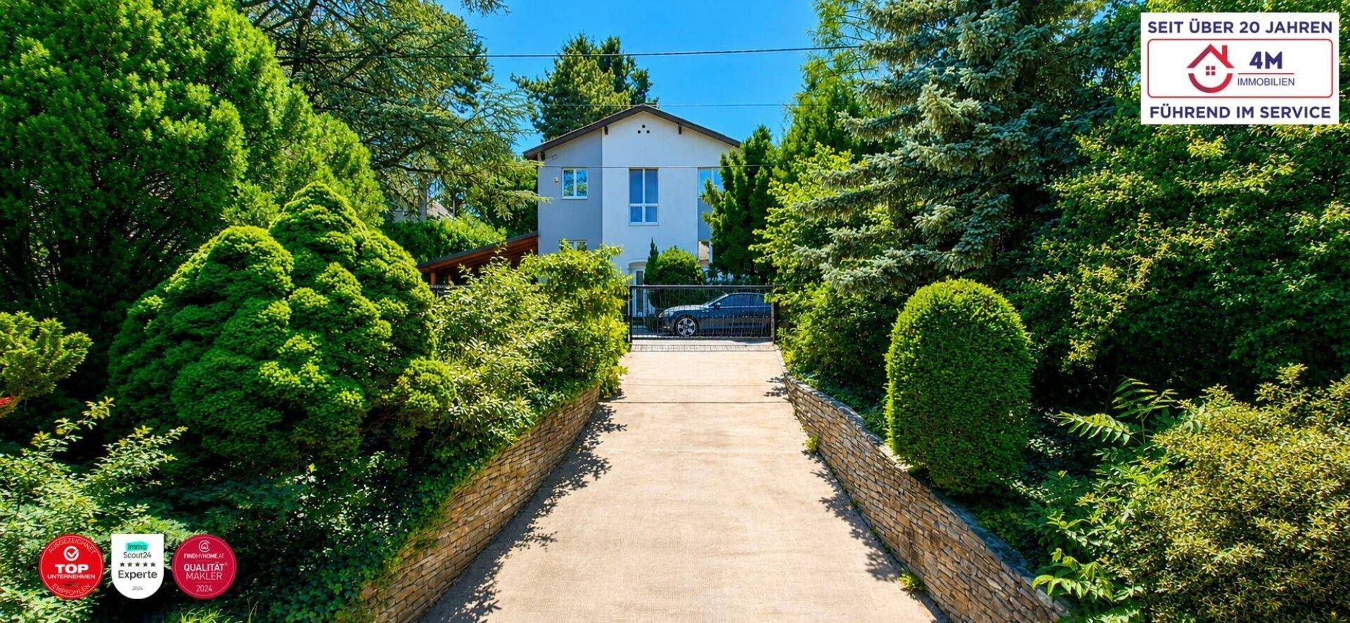 Lange Auffahrt zum Haus, umgeben von gepflegten Hecken und hohen Bäumen.