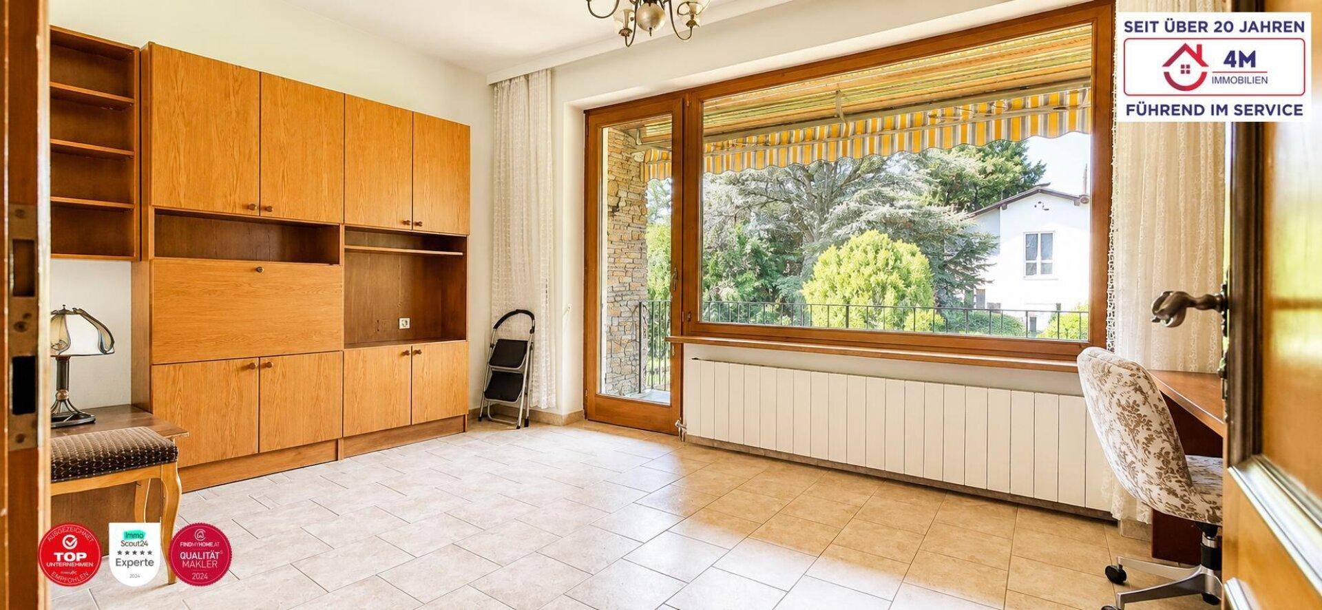 Helles Arbeitszimmer mit großem Fenster, Einbauschränken und Fliesenboden.