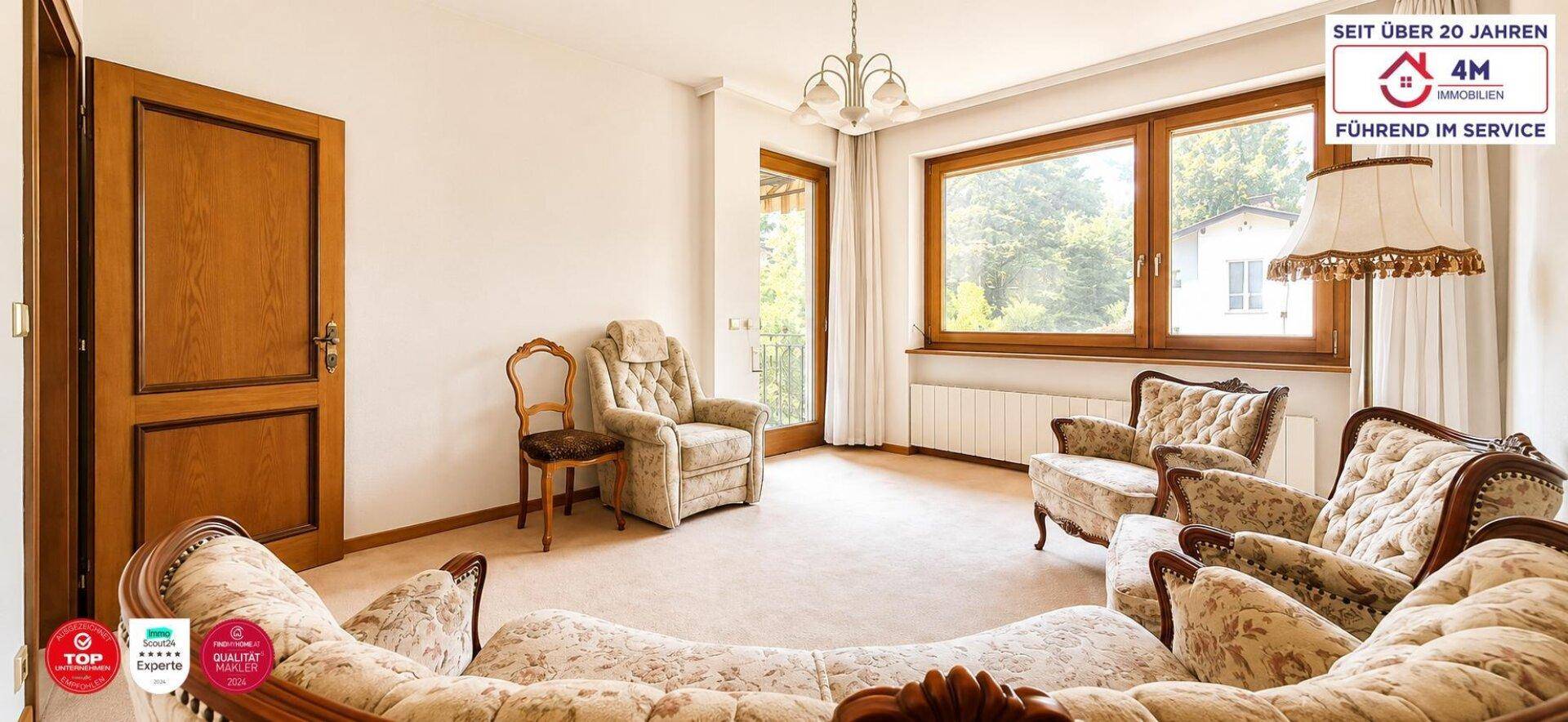 Gemütliches Wohnzimmer mit Teppichboden, bequemen Polstermöbeln und großen Fenstern.