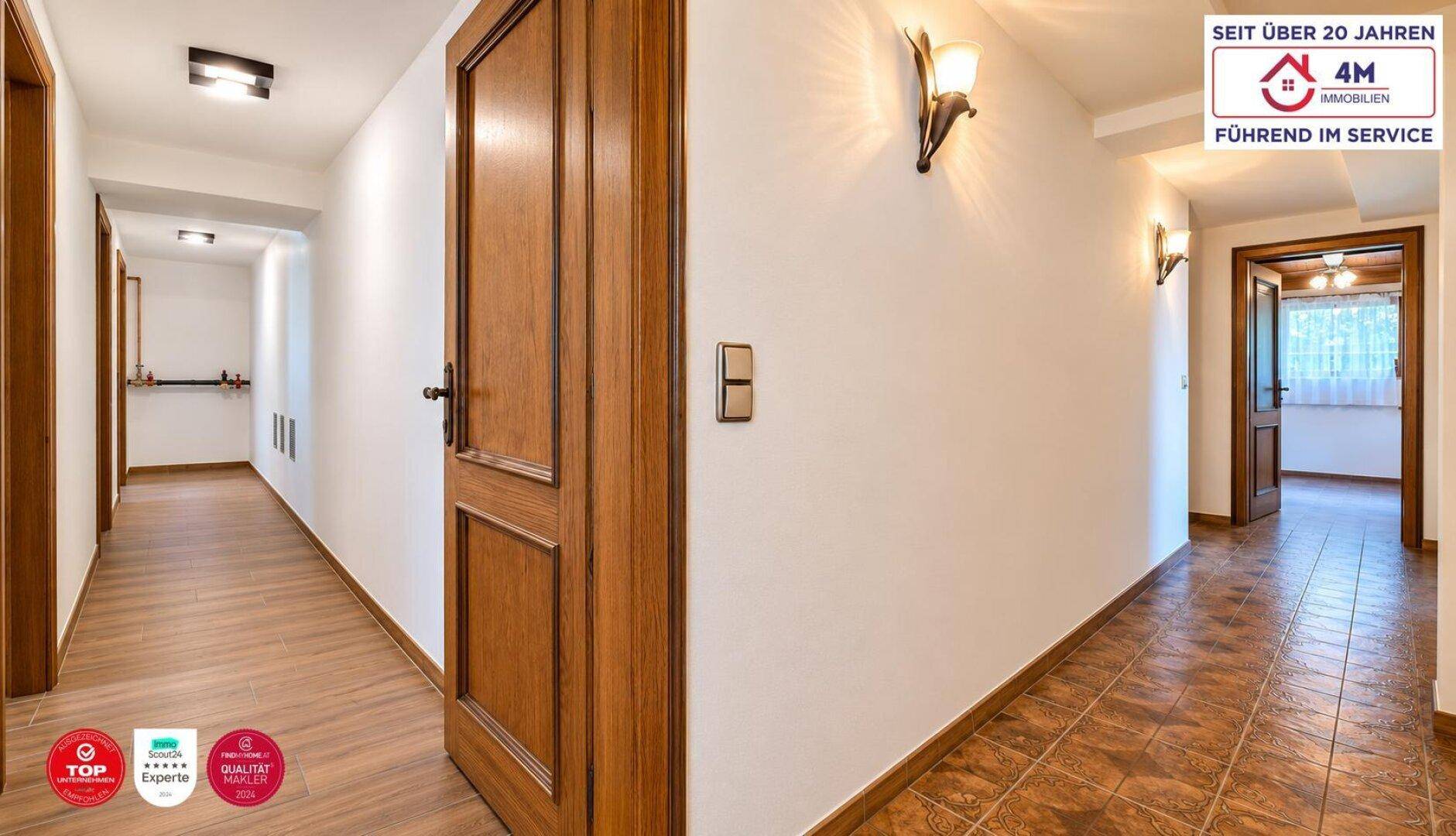 Heller Flur mit Holzböden, Holztüren und Wandleuchten, die eine warme Atmosphäre schaffen.