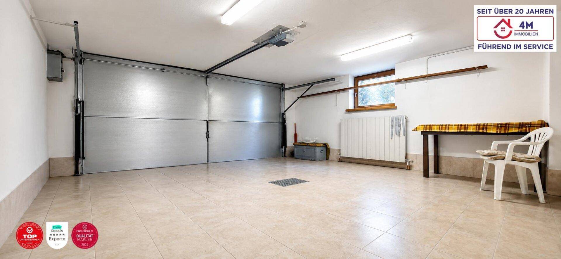 Geräumige Garage mit Fliesenboden, großem Tor und Fenster für Tageslicht.