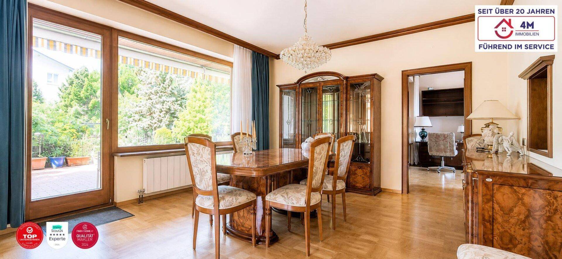 Heller Essbereich mit großem Holztisch, eleganten Stühlen und Blick ins Grüne.