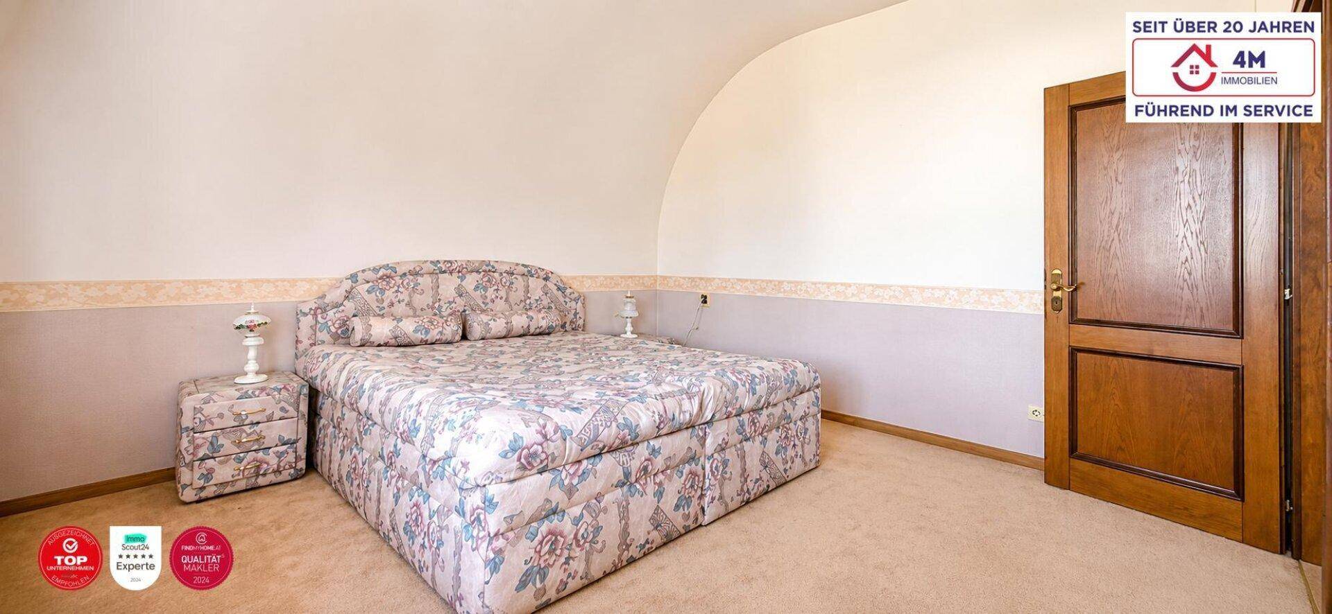 Ruhiges Schlafzimmer mit Teppichboden, gemustertem Bett und gewölbter Decke.