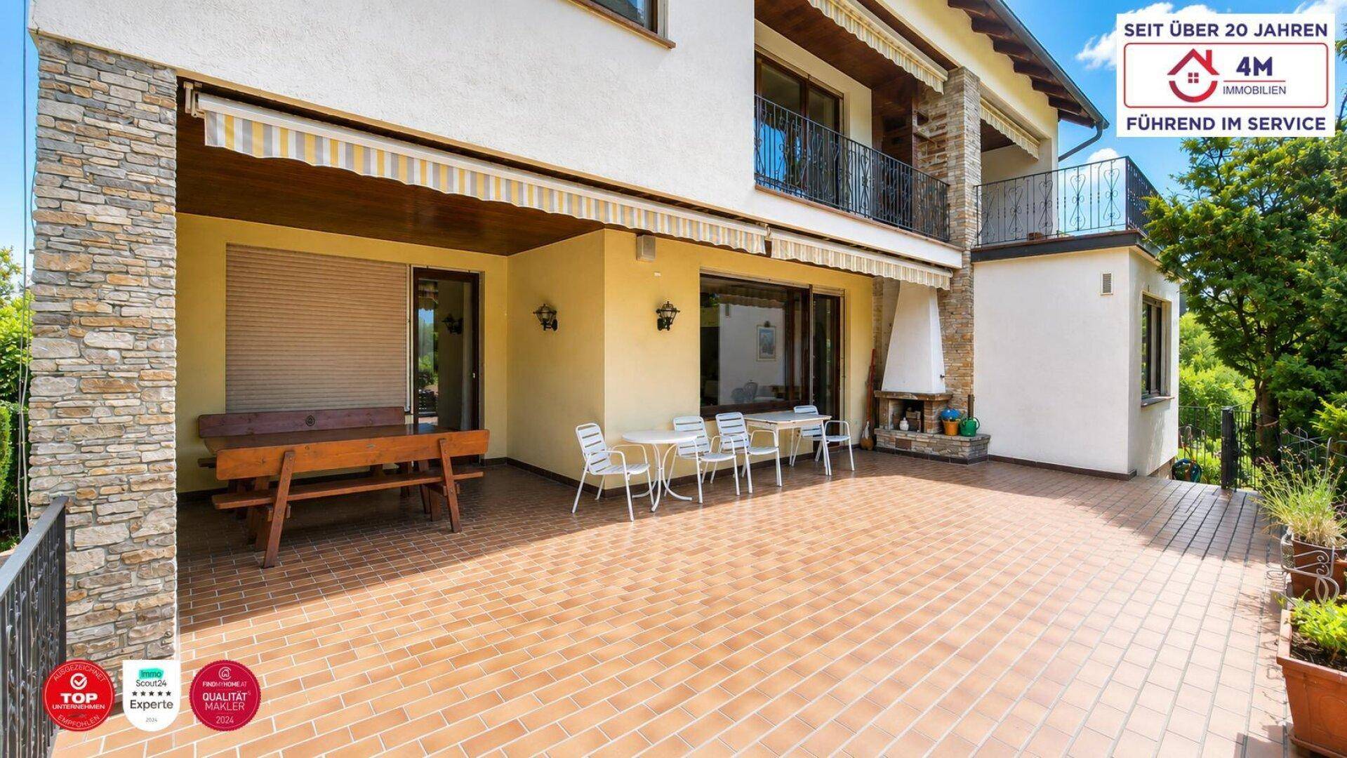 Große, geflieste Terrasse mit Markise und Sitzgelegenheiten, ideal für entspannte Stunden im Freien.