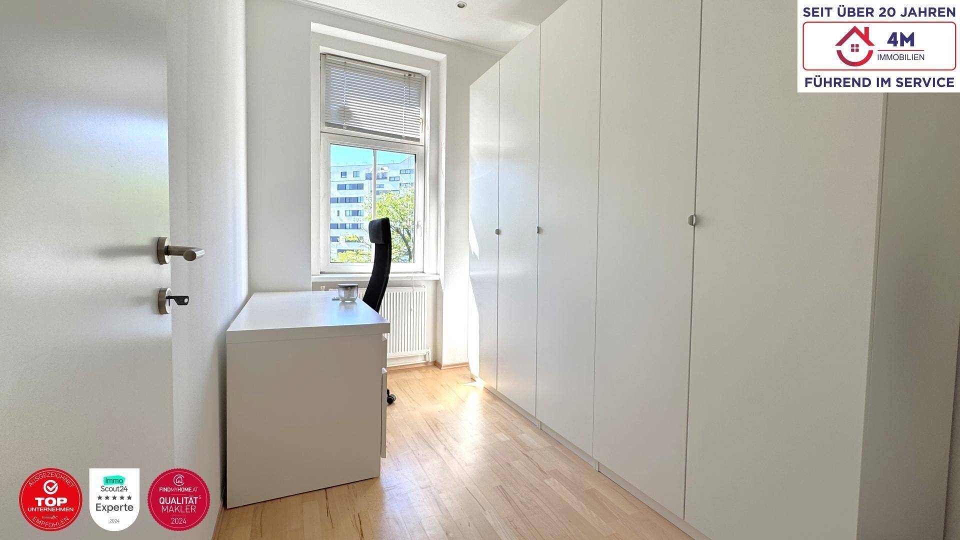 Arbeitszimmer mit Einbauschränken, Schreibtisch und Fenster, das den Raum hell erscheinen lässt.